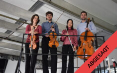 Vier Musiker stehen auf einer erhöhten Bühne und halten eine Geige, eine Bratsche, eine Flöte und ein Cello in den Händen; in der Ecke ist ein rotes Transparent mit der Aufschrift „ABGESAGT“ zu sehen.