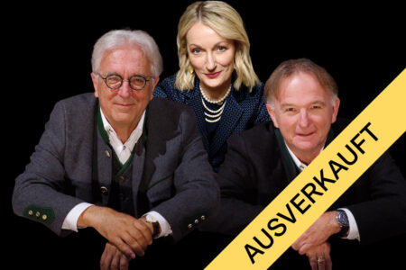 Drei Personen posieren vor einem schwarzen Hintergrund, über das Bild verläuft diagonal ein gelbes Banner mit der Aufschrift „AUSVERKAUFT“.